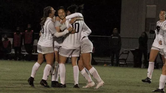 Women's soccer team huddles following a goal