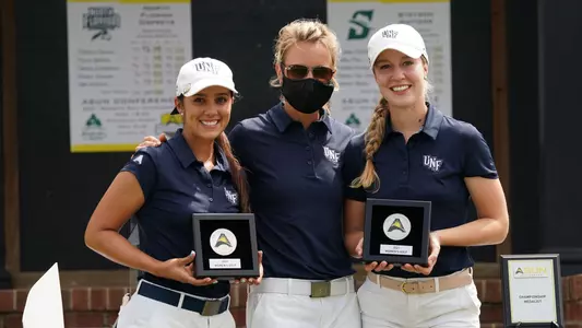 Mindy Herrick and Christin Eisenbeiss pose with head coach Joanne Berglund holding their plaques for earning ASUN All-Tournament honors
