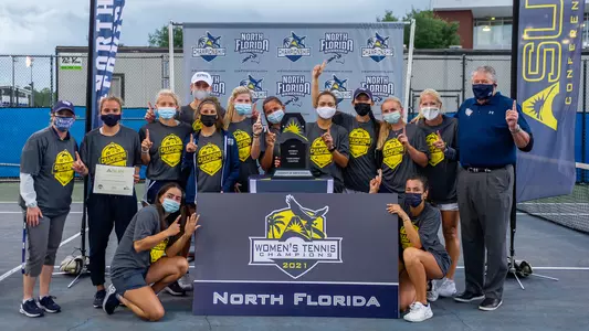 Women's tennis team poses with ASUN trophy - fully masked
