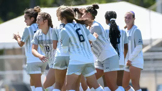 Women's soccer team huddles after scoring a goal