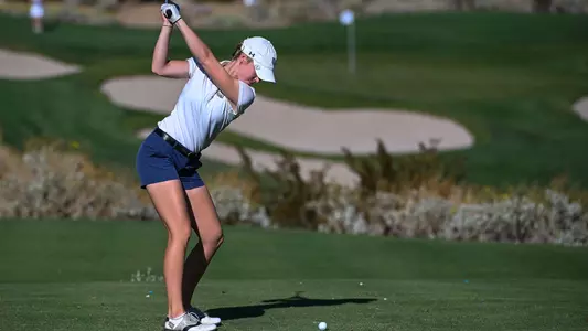 Christin Eisenbeiss hits a tee shot towards the green in the background