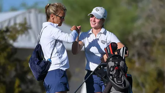 Christin Eisenbeiss fist bumps head coach Joanne Berglund on the tee box