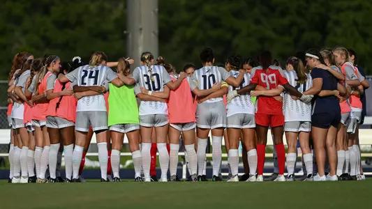 Women's soccer team huddles at bench before the match