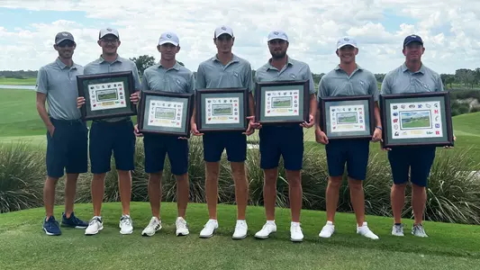 UNF men's golf team posing with team title plaques