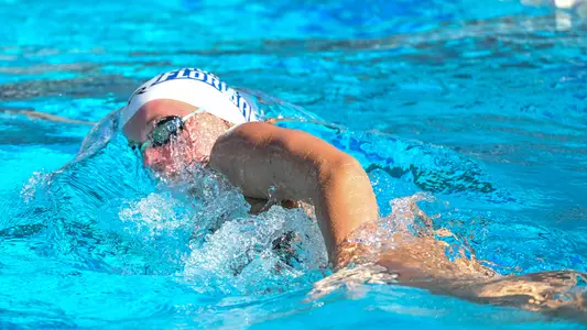 Faith Mutschler swimming freestyle in a white cap