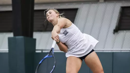 UNF Women's Tennis action shot with Summer Yardley following through her overhead smash.