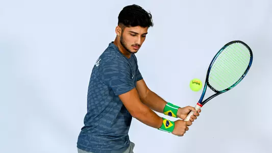 Breno Marques hitting a backhand, white backdrop