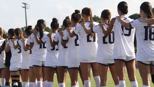 UNF women's soccer national anthem with a flag in the background