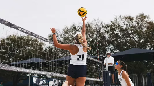 Mackenzie Murphy tipping the ball over the net at the The Coop Beach Volleyball Complex