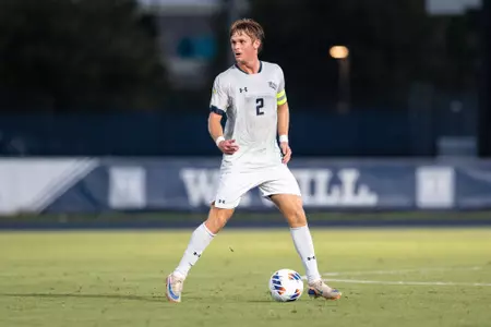 UNF Men's soccer player dribbles the ball.