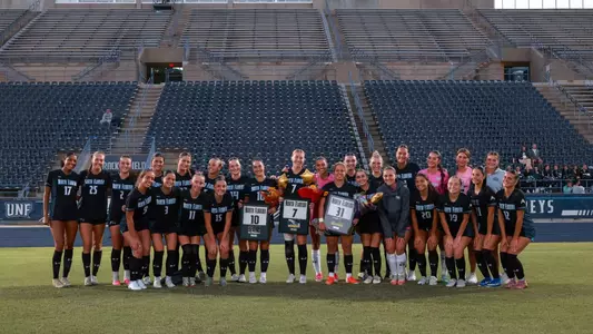 UNF Women's soccer team celebrates senior night by posing for a photo.