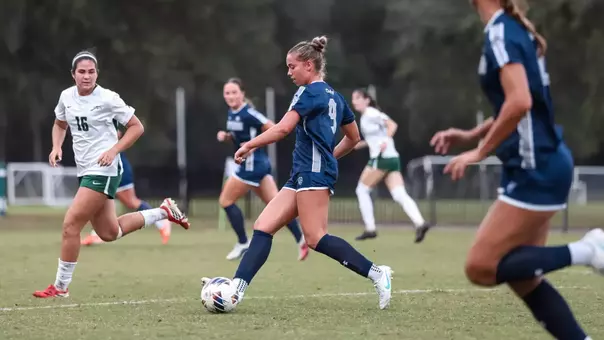 UNF Women's soccer player passes the ball.