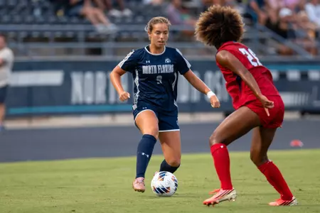 UNF women's soccer player dribbles towards a defender