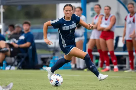 UNF Women's soccer player dribbling.