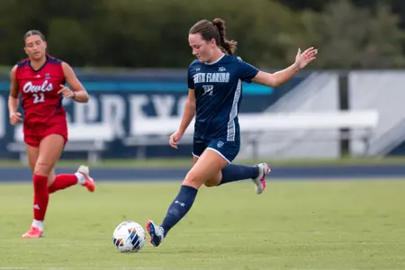 UNF women's soccer player kicks a ball with her right foot.