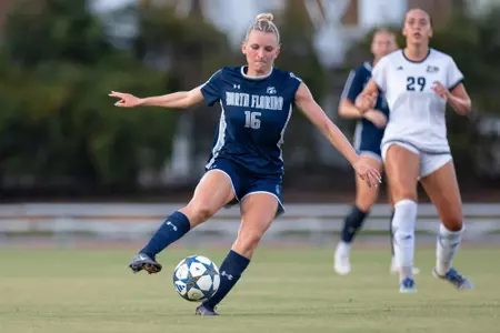 UNF Women's soccer player dribbles a ball.