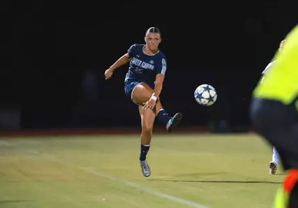 UNF Women's soccer player kicking a ball into the air.