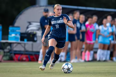UNF Women's soccer player dribbles the ball.