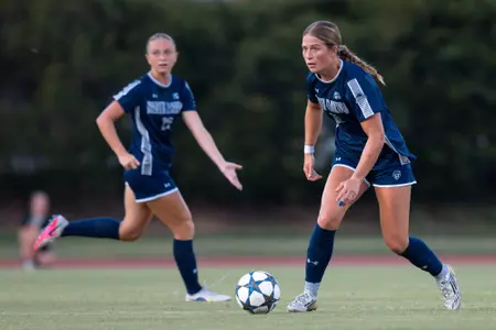 UNF Women's soccer player dribbling the ball with teammate behind her