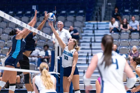 UNF Volleyball player reaching for ball over net