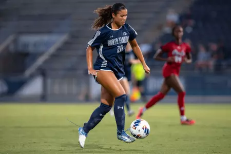UNF Women's soccer player dribbles the ball in the air.