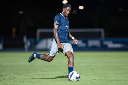UNF men's soccer player kicks a ball.