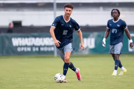 UNF Men's soccer player dribbles the ball