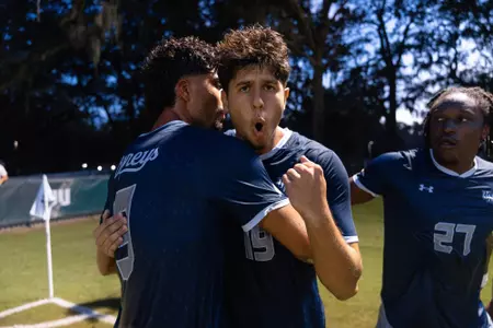 UNF Men's soccer player celebrates a goal scored by yelling and pumping his fist.