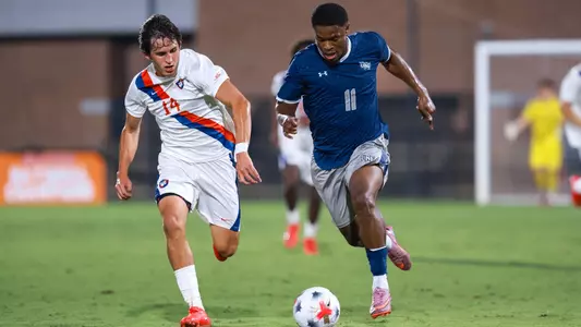 Alex Monde dribbles by a defender