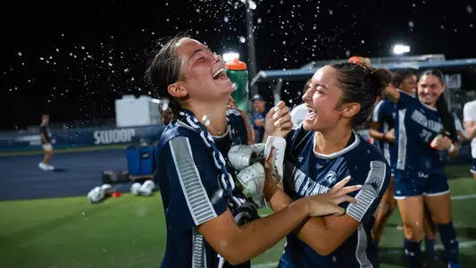 UNF Women's soccer players celebrate a win by pouring water on player.