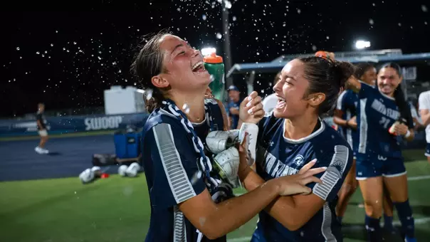 UNF Women's soccer players celebrate a win by pouring water on player.