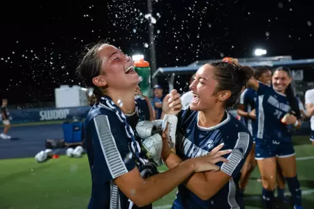UNF Women's soccer players celebrate a win by pouring water on player.