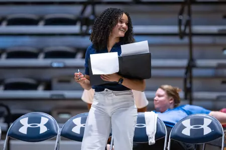 Volleyball Assistant Coach Kailey McKnight smiles at player.