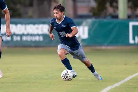 UNF Men's soccer player dribbles the ball.