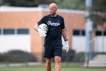 UNF men's soccer assistant coach holds soccer ball before the match.