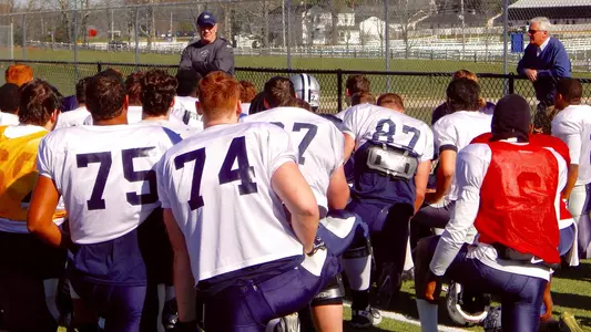 UNH President Mark Huddleston, right, stopped by football practice last week and commended four Wildcats who came to the aid of a state trooper.