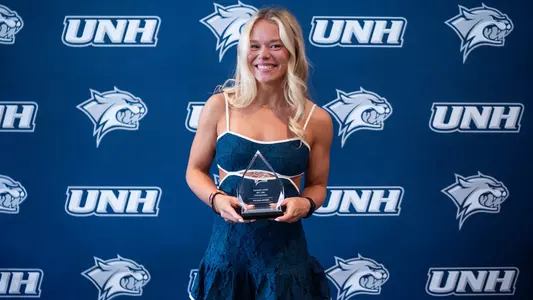 UNH junior gymnast Poulina Minaev poses with her 2026 Unsung Hero Award