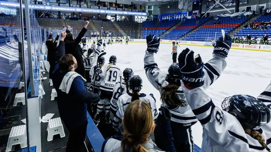 UNH women's hockey celebrates a goal from the bench.