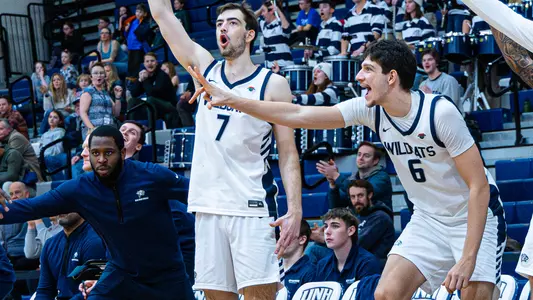 John Squire and Giannos Xanthopoulos celebrate on the UNH men's basketball bench