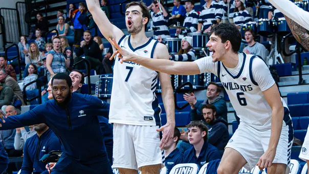 John Squire and Giannos Xanthopoulos celebrate on the UNH men's basketball bench