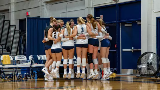 Volleyball celebrates in a team huddle.
