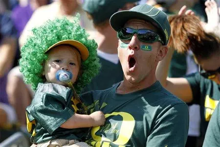 An Oregon fan reacts while holding a child