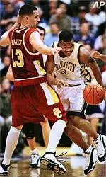 Adam Spanich tries to prevent<br>Washington's Senque Carey<br>from driving to the hoop.