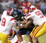 Southern Cal defenders including Tyler Davis (9) and Chris Barrett bring down Arizona wide receiver Michael Thomas, center, in the first half. (AP Photo)