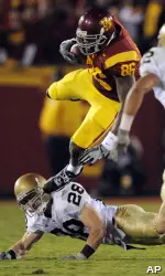 Anthony McCoy jumps over Notre Dame safety Kyle McCarthy as he runs the ball during the first half.
