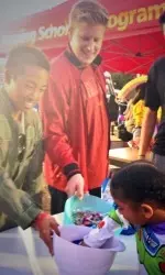 Athletes Paul Yoder and Tommy Van offer Halloween candy to local kids.