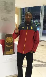 Just'N Thymes posing by one of USC's NCAA Championship trophies.