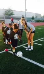 Freshman midfielder Abigail Callahan instructs young kids while they practice their dribbling skills.