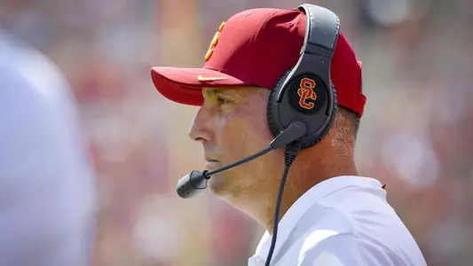 Clay Helton wears his headset at the UNLV gave and watches the field.