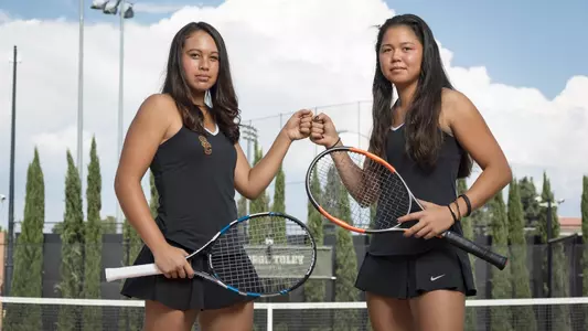 Angela Kulikov and Rianna Valdes fist bump on the tennis court.